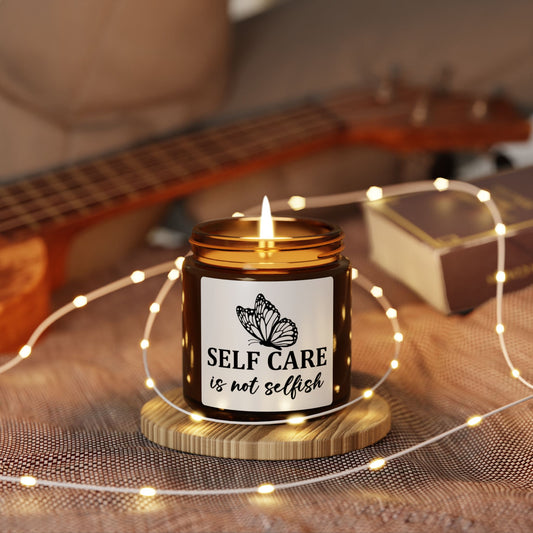 Candle with 'Self Care is not Selfish' label on a wooden coaster with fairy lights, guitar in the background