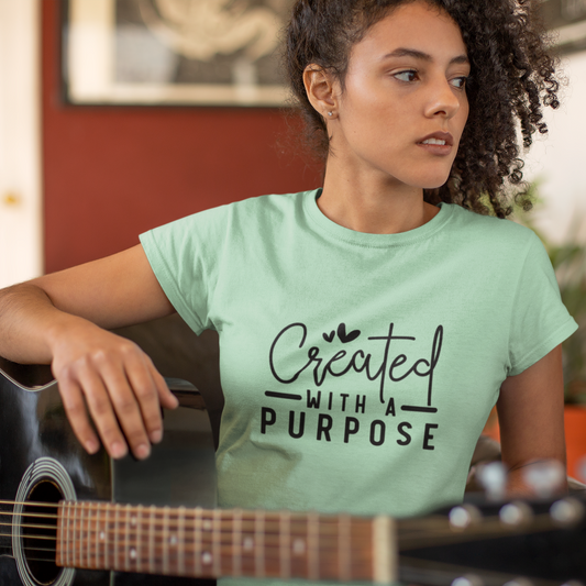 Woman wearing a light green t-shirt with 'Created with a Purpose' text, holding a guitar.