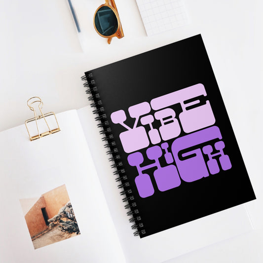 Black notebook with purple text on a white surface with a photo and sunglasses.