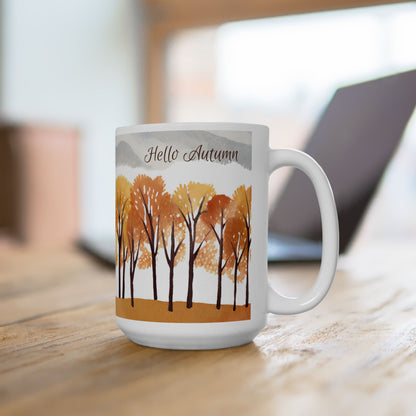 White mug with autumn-themed design featuring trees and 'Hello Autumn' text on a wooden surface.