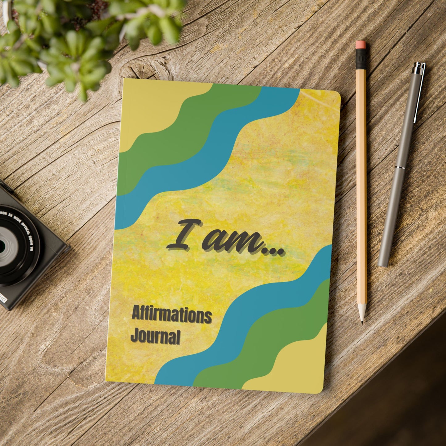 Notebook titled 'I am... Affirmations Journal' on a wooden surface with a pen and pencil.
